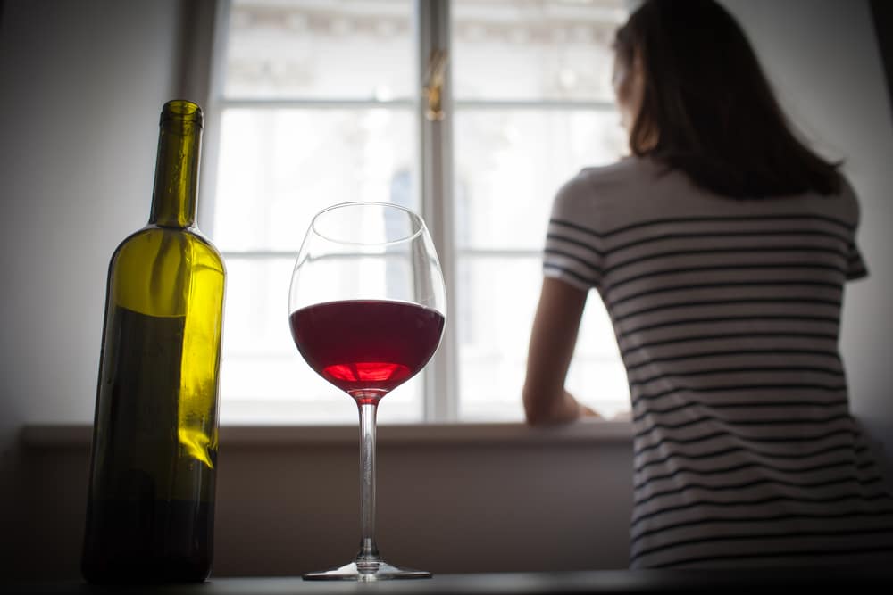 woman looking at window drinking wine